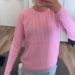 Rosa kabelstickad tröja från Ullared - Supersöt ljusrosa kabelstickad tröja från Best You i mjuk bomull. Klassisk rund halsringning och långa ärmar. Perfekt för dig som gillar en preppy vibe och vill ha något som sticker ut lite extra i garderoben.