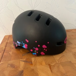 Svart cykelhjälm med rosa detaljer  - Super fin svart cykelhjälm. I väldigt bra skick. Storlek M för barn men även vuxenstorlek