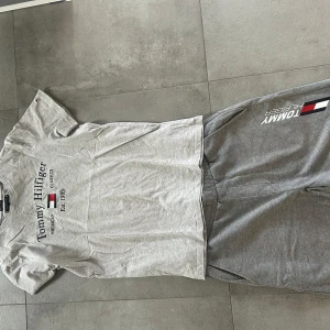 Grå t-shirt&shorts Tommy Hilfiger - Säljer min snygga Tommy Hilfiger dress pga av att jag inte använder den längre. Köpte den förra året. Den är som helt ny inga hål, inte sliten nånstans. Storlek på t-shirten är 176 och på shortsen storlek S (passar M)