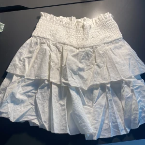 Vit volangkjol med smock - Supersöt vit kortkjol med bred smock i midjan och dubbla volanger.