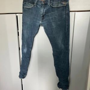Blå Replay jeans med klassisk tvätt - Snygga blå jeans från Replay med klassisk tvätt och diskreta slitningar.Har Replay-logga på bakfickan och myntfickan. Perfekta för en avslappnad stil. Storleken är W32 L32  och den sitter  slim. Priser kan sänkas!!