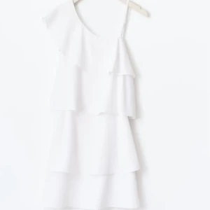 Vit omlottklänning med volanger - Superfin vit kortklänning med volanger i flera lager och asymmetrisk axel, där ena sidan har smalt axelband och den andra är offshoulder. Helt oanvänd glömde lämna tillbaka den i butik inom 30 dagars tiden . Storlek 164/S