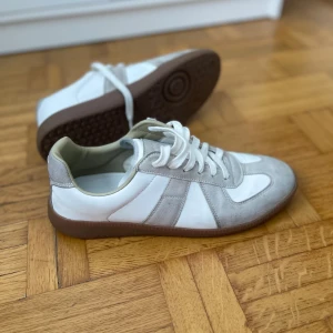 Maison margiela vit/grå - Ett par nästan oanvända maison margiela skor som är perfekta nu till sommaren. Varför jag säljer är för att dom var för små för mig. Priset kan diskuteras vid snabb affär. Kan skicka fler bilder om du ör intresserad.