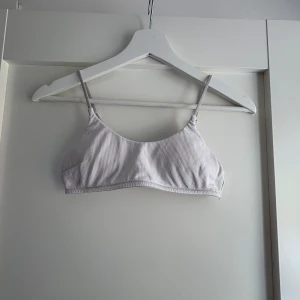 Vit ribbad bralette - Säljer en vit ribbad bralette med smala justerbara axelband. Materialet är mjukt och stretchigt för en bekväm känsla hela dagen. Använd fåtal gånger. Strl 36