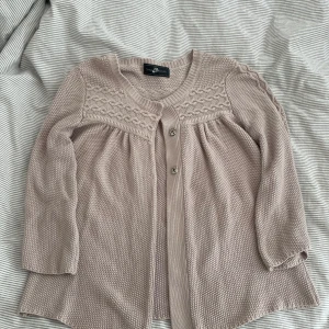 Rosa stickad kofta  - Supersöt rosa stickad kofta från Style Butler med trekvartsärm och fina flätade detaljer upptill. Koftan har rund halsringning, tre knappar framtill och ett luftigt, lite vidare fall. Perfekt att slänga över ett linne för en chill look.