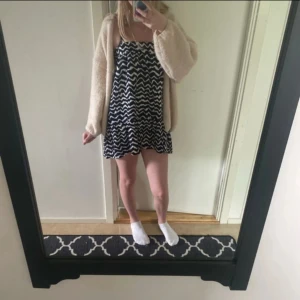 Klänning  - Supersöt kort klänning med blåttvitt vågigt mönster utan axelband. Klänningen har en lös passform och volang nertill, perfekt för en chill och trendig look. Materialet känns lätt och flowy, perfekt för varmare dagar.