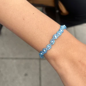 Blått pärlarmband med blommönster - Superfint armband med små blå pärlor som bildar ett blommigt mönster. 