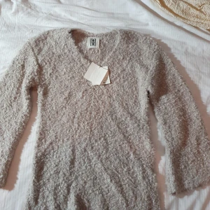 Beige stickad tröja med v-ringning - Supermjuk och fluffig beige stickad tröja från Hunkydory. Tröjan har v-ringning, lång ärm och en riktigt cozy textur som känns lyxig. Perfekt för lager-på-lager och chill höst- och vinteroutfits.