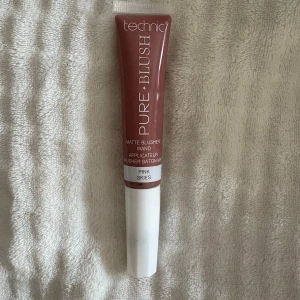 Technic Pure Blush Matte Blusher Wand - Technic Pure Blush Matte Blusher Wand i nyansen Pink Skies. Flytande rouge i tub med mjuk applikator för enkel applicering. Ger en matt finish och en naturligt rosig ton till kinderna. Perfekt för dig som vill ha en smidig och snabb blush-rutin.