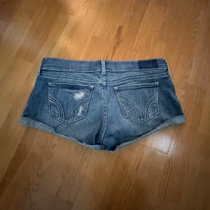 Blå jeansshorts från Hollister - Snygga low waist blå jeansshorts från Hollister med slitna detaljer och uppvikta benslut. Dem är knappt andvända och är super fina på💕TRYCK INTE PÅ KÖP NU!!
