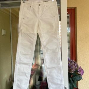 Vita raka jeans från Fornarino - Snygga vita jeans från Fornarino med raka ben och klassisk femficksdesign. Byxorna har normal midja, bälteshällor och silverfärgade nitar. Materialet är bomull 70% och polyester 30 % med en mjuk känsla. Storlek 25. 