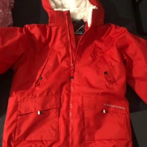 Röd vinterjacka Cross Sportswear - HELT NY, Riktigt snygg röd vinterjacka från Cross Sportswear med mysigt vitt teddyfoder i huvan. Jackan har dragkedja, stora fickor framtill och coola detaljer. Perfekt för kalla dagar när du vill hålla stilen och värmen. Storlek på bilderna