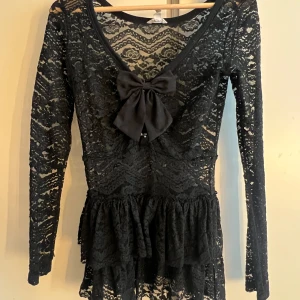 Gothic spetstopp  - Supersöt svart gothic spetstopp från Bethany Mota med långärmade spetsärmar och v-ringning. PERFEKR FÖR LAYERING MED KJOL UNDER! Rosetten på första bilden ingår inte med toppen (se bild 2) men kan köpas tsm med toppen för extra 20kr🫶 säljer pga att den är för liten för mig eftersom ärmarna är väldigt tighta/smala