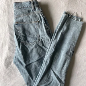 Ljusblå jeans från ASOS DESIGN 26/34 - Snygga tall ljusblå jeans från ASOS DESIGN med en klassisk femficksdesign. De har en fransig kant vid bensluten och en knappgylf. 