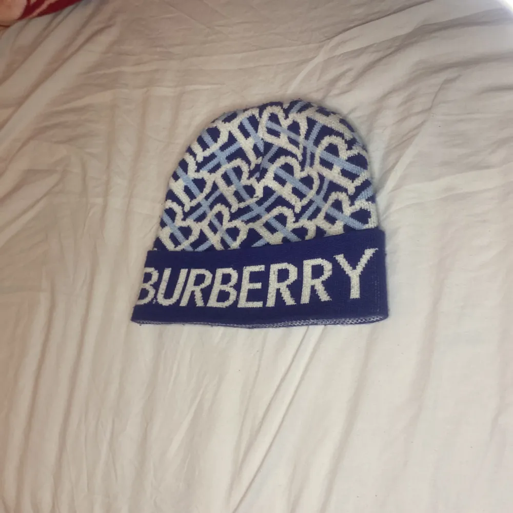 Snygg blå och vit mössa från Burberry med ett unikt mönster och logotyp framtill. Perfekt för att hålla stilen i kallare väder.. Asusteet.