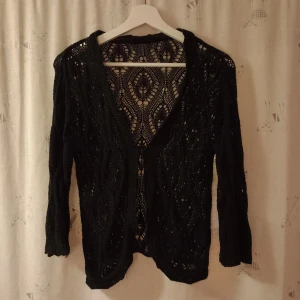 Svart spetskofta - Snygg svart kofta med spetsmönster. Koftan har långa ärmar och en öppen design framtill.