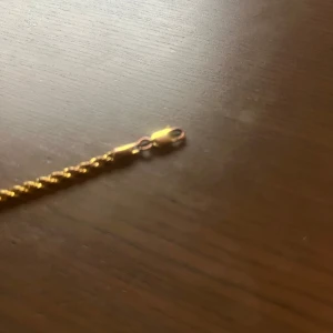 Guldarmband - Elegant guldarmband med en stilren tvinnad design. Perfekt för att lägga till en touch av lyx till din outfit. Armbandet har en smidig låsmekanism för enkel användning.