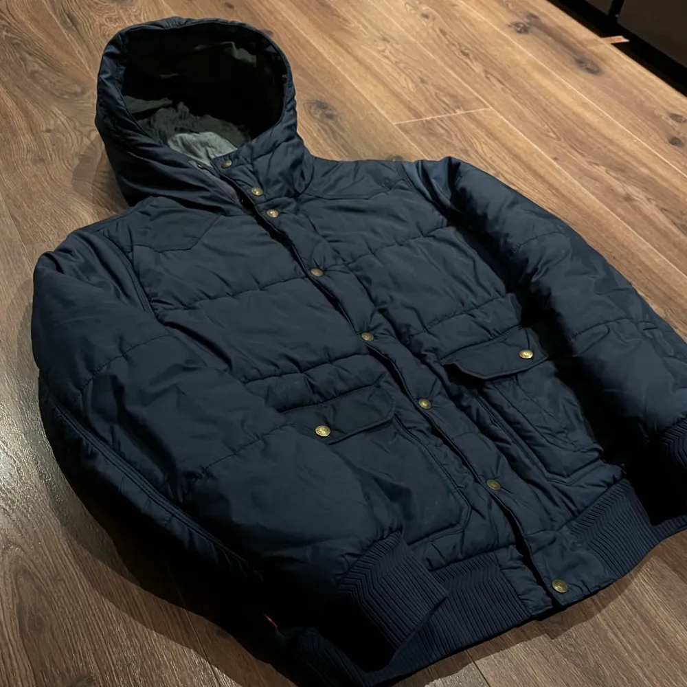 Säljer en snygg mörkblå pufferjacka från Levi's. Jackan har en huva och stängs med både dragkedja och knappar. Perfekt för kyliga dagar med sin quiltade design och ribbade muddar. Använd men i fint skick ✅. Tveka inte på att kontakta om du har några frågor🤝🏼 nypris mellan 1100-1500kr. Takit.