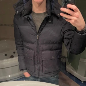 Massimo dutti jacka - Säljer en snygg mörkblå pufferjacka från Massimo dutti, Jackan har dragkedja och knappar framtill samt praktiska fickor med knappar. Perfekt för kyliga dagar!