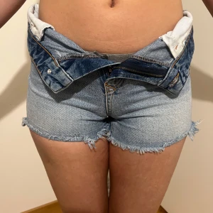 Jeansshorts från Pieces - Snygga jeansshorts från Pieces med fransiga kanter och klassisk femficksdesign. Perfekta för sommardagar och festivaler. De har en knapp och dragkedja framtill för enkel stängning. Midjemåttet tvärsöver 35. Tighta på mig.