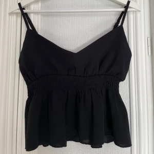Svart ärmlös topp med smockdetaljer - Snygg svart ärmlös topp med smockdetaljer och justerbara axelband. Använd ett fåtal gånger. Storlek S❣️