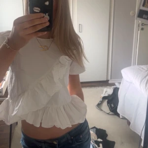 Vit blus med volang - En vit topp med volanger från By Malina. Storlek xs