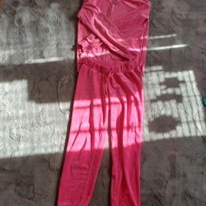 Rosa mjukisbyxor med dragkedja - Säljer ett par rosa mjukisbyxor med matchande överdel. Byxorna har en bekväm passform och är gjorda i ett mjukt material. Perfekta för en avslappnad dag hemma. Överdelen har dragkedja och muddar vid ärmsluten. Ena sidan har snöret åkt bak. 146/152 på byxorna och 158/164 på överdel men passar mig med xs/160 cm