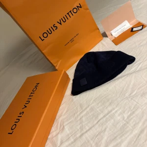 Mörkblå mössa från Louis Vuitton - Säljer en stilren mörkblå mössa från Louis Vuitton. Mössan har ett diskret rutmönster och en uppvikt kant. Perfekt för att hålla värmen med stil. Köpt i butik, kommer med kvitto, box, bag med mera! Priset kan diskuteras vid snabbaffär! Är även öppen för byten! 