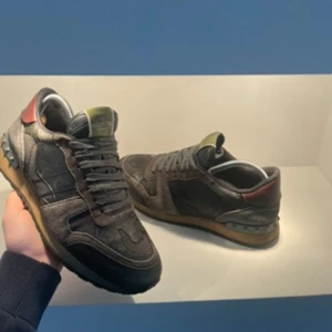 Valentino Rockrunner sneakers i grått och rött - Snygga Valentino Rockrunner sneakers i en cool kombination av grått och rött. Skorna har en klassisk snörning och en robust sula. Perfekta för dig som vill ha stil och komfort i ett.