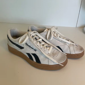 Reebok sneakers - Classic CLUB C GROUNDS  - Snygga vita sneakers från Reebok med svarta detaljer och brun sula. Endast använda en gång men har blivit lite smutsiga på tårna samt noppriga vid hälen på insidan men verkligen ingenting man tänker på! Säljer då de inte passade mig men det är verkligen så sköna 💗🌸