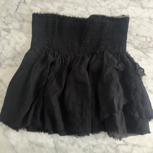 Svart minikjol från Zadig & Voltaire i 100% siden - Snygg svart kjol från Zadig & Voltaire med en elastisk midja och volangdetaljer. Kjolen har en kort längd och är perfekt för en trendig look. Tillverkad i ett lätt och luftigt 100% siden som ger en skön känsla och lyxig look. Använd ett fåtal gånger. Köpt för 2995kr. Den perfekta svarta mini kjolen med lite volang! Passar xs-m