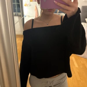 Svart offshoulder tröja - Säljer en svart offshoulder tröja med en croppad design. Tröjan har långa ärmar som går ut lite längre ner och har en bekväm passform. 