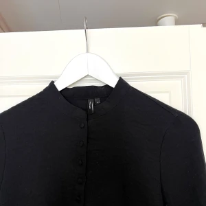 Svart långärmad tröja med knappar - Snygg svart långärmad tröja med knappar framtill. Perfekt för en stilren look. Passar bra till både jeans och kjol.