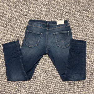 Blå jeans från Replay - Snygga blå jeans från Replay med en klassisk femficksdesign och knappgylf. Jeansen har en slim passform och är perfekta för en stilren look. Tillverkade i ett slitstarkt denimtyg.