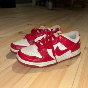 Nike Dunk low röda  - Supercoola röda Nike dunks. Jag köpte till creaseskydd som kommer med i skorna, som skyddar dem från att creasas. Dessa går att ta ut! Skorna är väl använda men tack vare skyddet är de fortfarande i relativt bra skick! Nypris 1500kr