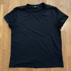 Svart basic t-shirt från Bik Bok - En svart, klassisk t-shirt från Bik Bok i mjuk bomull. Modellen är enkel med rund hals och korta ärmar. Passformen är normal och tyget känns skönt mot huden. 