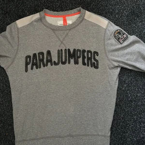 Grå sweatshirt från Parajumpers - Snygg grå sweatshirt från Parajumpers med orangea detaljer. Använd men i utmärkt skick!