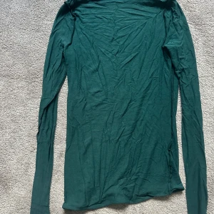 Mörkgrön långärmad tröja Intimissimi - Superskön mörkgrön långärmad tröja från Intimissimi, gjord i en mjuk blandning av ull och kashmir. Tröjan har en slim passform och är perfekt för lager-på-lager under hösten och vintern. Enkel design utan mönster eller detaljer, bara ren och stilren.