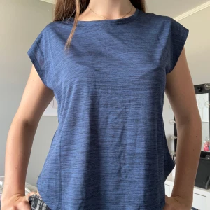 Blå träningstopp - Snygg blå linnetopp med diskret randigt mönster. Toppen har en loose passform och är ärmlös med rund halsringning. Perfekt för dig som gillar enkel och stilren design. Materialet känns lätt och skönt mot huden.