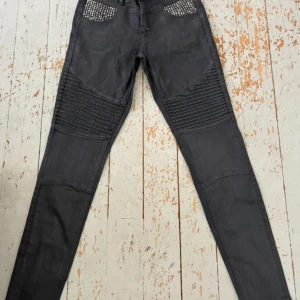 Svarta skinny jeans från Mos Mosh - Snygga svarta jeans från Mos Mosh med skinny passform. Framtill har de coola ribbade detaljer på låren och fickor med silvriga nitar som ger en edgy vibe. Jeansen är tillverkade i ett stretchigt bomullsmaterial för skön komfort och sitter tajt hela vägen ner.