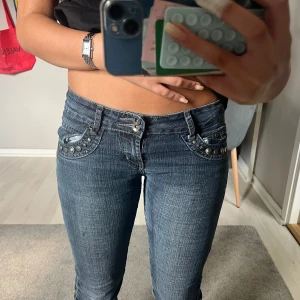 Unika blå bootcut jeans med nitar - Snygga blå jeans från med låg midja och bootcut passform. Jeansen har coola silverfärgade nitar på fickorna och tydliga vita sömmar som ger en edgy vibe. Materialet är klassisk jeans med lätt tvättad look. Perfekta för dig som gillar detaljer och vill sticka ut. 💕Jag är 160. Innerbenslängd: 79 midjemått:36 så totalt 72❣️midjan är överlag väldigt stretchig