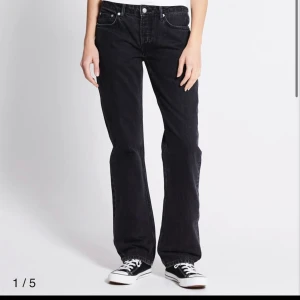Svarta  jeans  - Jeans med låg midja och rak passform. Fickor fram och baktill. Knappgylf samt hällor för bälte. Jeansen är en fullängdsmodell gjord i en denim i 100% bomull utan stretch.