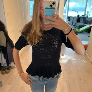 Mörkblå stickad topp med volang - Supersöt mörkblå stickad topp från Holly & White med korta ärmar och volangkant nedtill. Tröjan har ett snyggt hålmönster som gör att hela tröjan blir finare. Köpte den för länge sen men har aldrig använt den. Den är en skit snygg tröja och är så fin på kroppen 