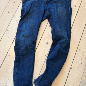 Lee Luke jeans blå W33 L32 - Snygga mörkblå jeans från Diesel, modell Luke. Klassisk femficksdesign med raka ben och normal passform. Jeansen är gjorda i slitstarkt denim och har diskreta detaljer som ger en cool look. Perfekt för dig som gillar stilrena och tidlösa jeans. Slimfit