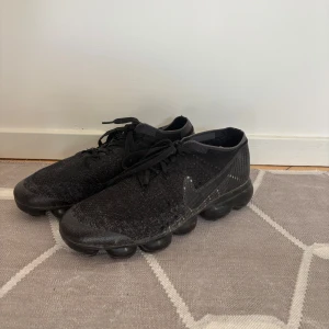 Nike Air Vapormax Black / Anthracite  - Svarta Nike Vapormax sneakers med stickad ovandel och studsig sula. Slitage runt snörningen. Nypris 1800kr. Säljes pga av att skorna bara stått i garderoben utan användning. 