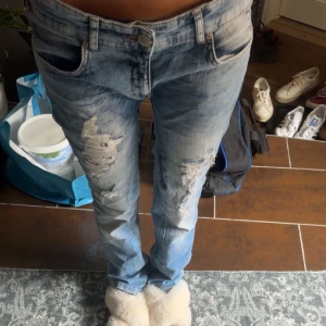 Ljusblå ripped jeans straight fit - Säljer ett par ljusblå jeans med snygga slitningar och ripped detaljer på låren. Modellen har klassisk femficksdesign, rak passform och normal midja. Köpta via plick, säljaren har sytt in jeansen så dom är för små för mig. Midja 40, innerben 82 cm. 