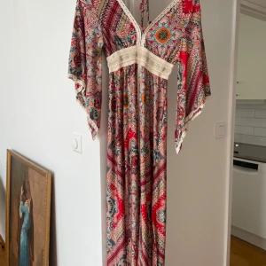 Lång paisleyklänning från BeniSSimo - Färgstark långklänning. Klänningen har har spetsdetalj i midjan och slits. Köpt i Grekland nypris 499kr