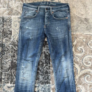 Blå slim fit jeans  - Snygga blå jeans med slitna detaljer och klassisk femficksdesign. Jeansen har slim passform och låg midja, med coola slitningar framtill och bak de har även några skvättar med färg på sig när man kollar noga. Materialet är jeans med en schysst tvättad look och kontrastsömmar. Perfekt för dig som gillar streetwear. Storleken är W28 L32 skulle säga att de känns som W29. Jag köpte de för runt 1,2 säljer de för endast 899.