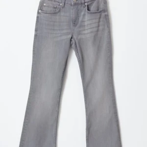 Grå bootcut jeans med låg midja - Snygga grå jeans med bootcut passform och låg midja. Jeansen har klassisk femficksdesign och är tillverkade i mjukt denim-material. Perfekta för dig som gillar en retro vibe och vill ha ett par jeans som sticker ut lite extra.