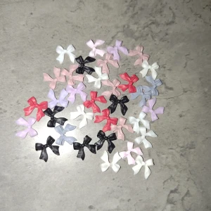 Nageldekoration - Ett paket med små dekorativa rosetter i olika färger. Perfekta att använda som nageldekoration för att ge dina naglar en gullig och personlig touch. 